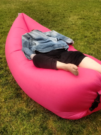 Moi, enfouie dans un bagchill rose, en robe longue noire, la tête planquée sous un blouson en jean.